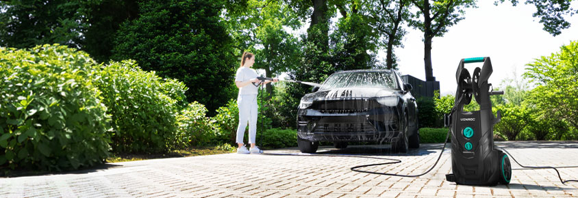 Une femme nettoie une voiture avec le nettoyeur haute pression VONROC V25.